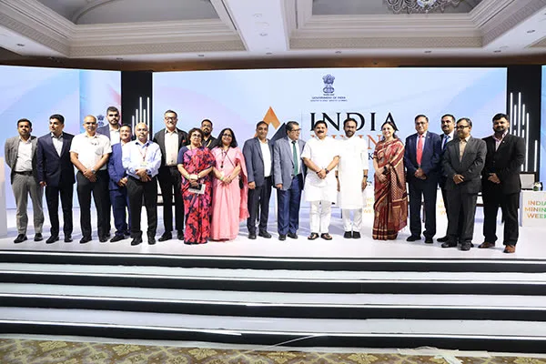 Dignitaries on stage at India Mining Week, with the Government of India emblem and event backdrop